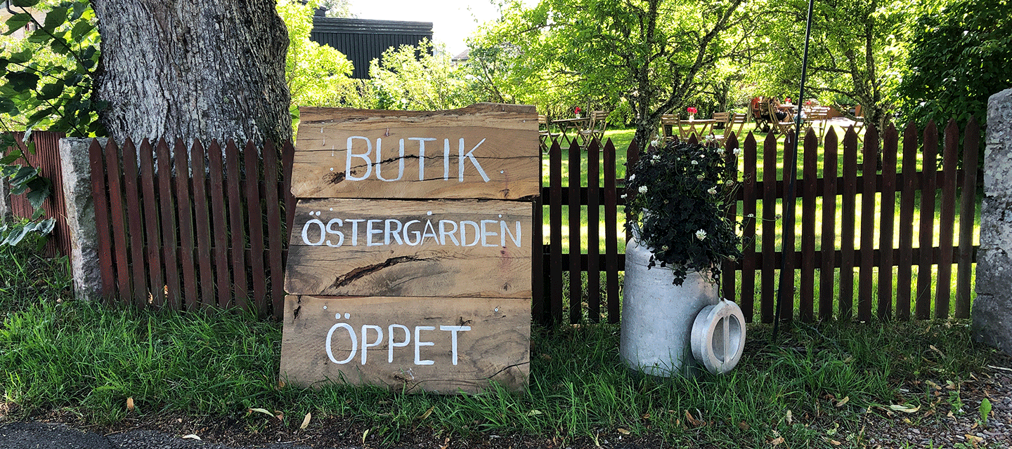 Bilden föreställer skylten som finns vid ingången till Butik Östergarden. En skylt i gammal stil med handskriven text.