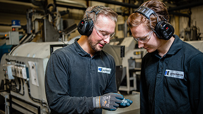 Två människor som står i en industrilokal. Båda två har hörselskydd på sig.